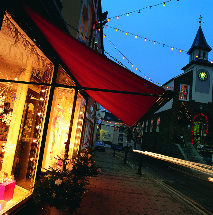 A shopping street in Narberth at dusk lit up with Christmas lights and decorations.