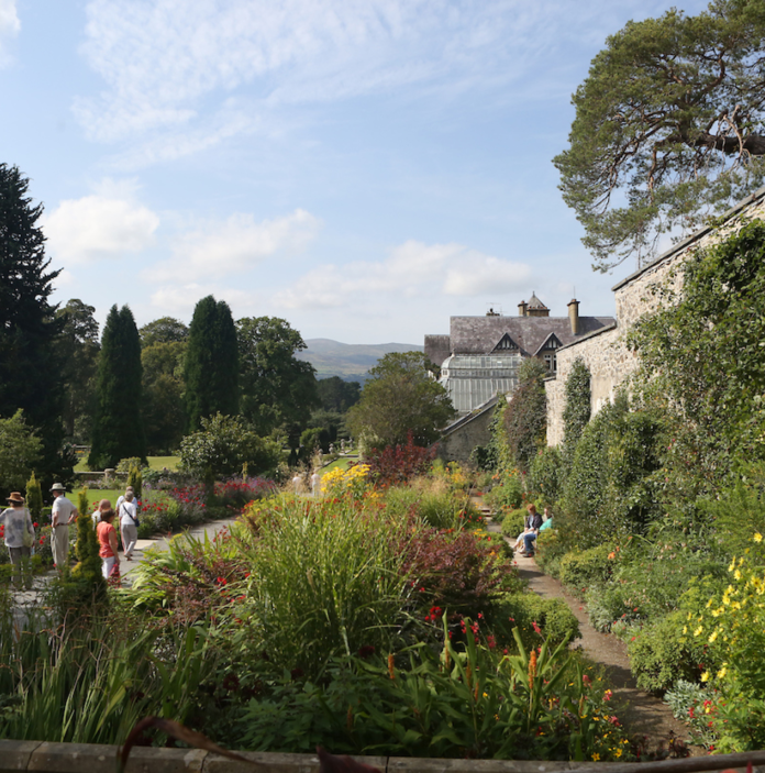 Walled gardens with flowers and plants and people walking at Bodnant Garden.