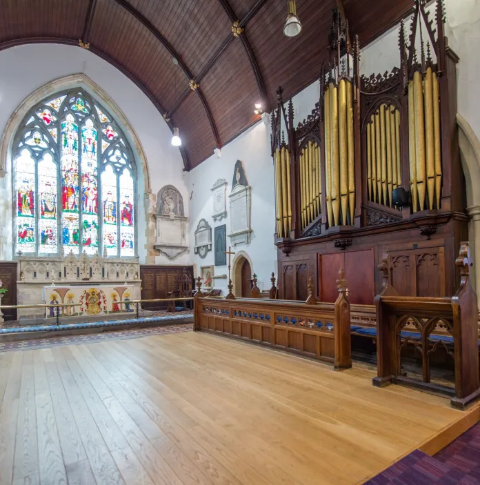 A pipe organ in a church with a large stained glass window.