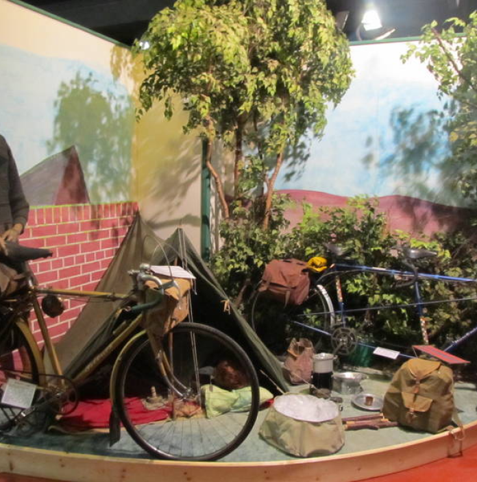 A camping scene with historic cycles on display at a museum.