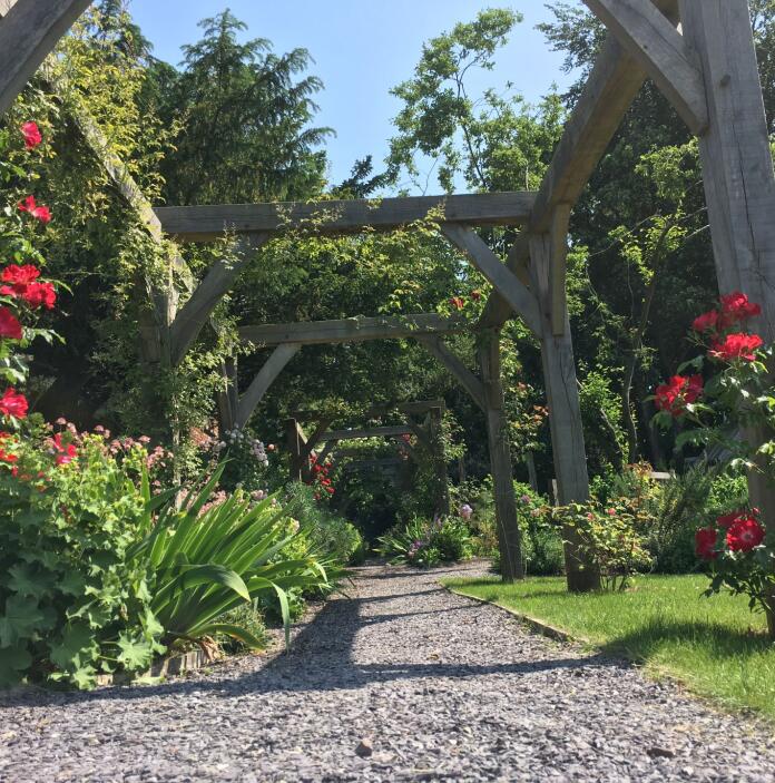 Flowers alongside an archway in a garden.