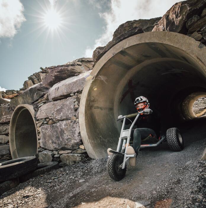A three wheel cart emerging from a pipe tunnel in a quarry.