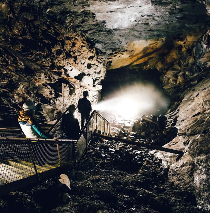 Group of people heading down stairs into an underground mine.