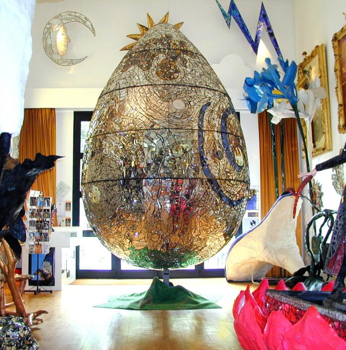 A giant vibrant egg on display with other vibrant artwork in a museum.