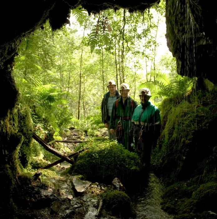 Group of people looking into a former mine in safety gear.
