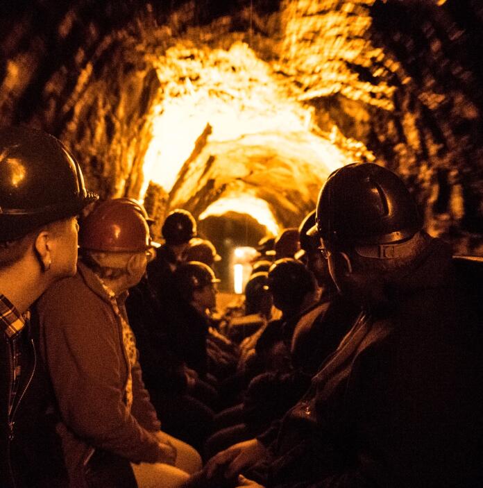 People wearing safety helmets travelling through a lit cave.