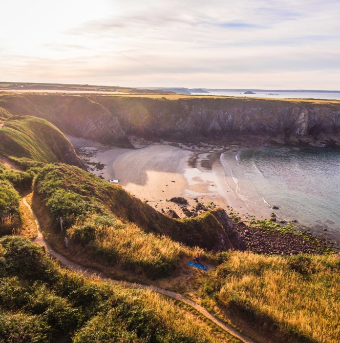 Views of a sandy bay along a coast path.
