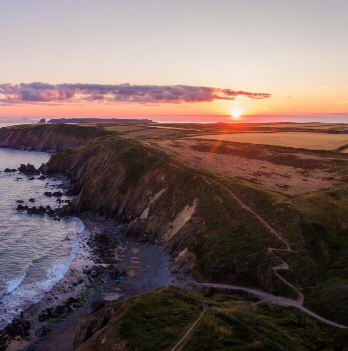 Coastal path with a sunset as a backdrop.