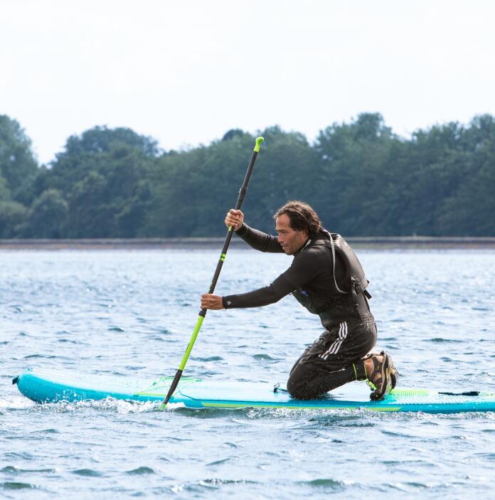 A man on a stand up paddleboard on a reservoir.