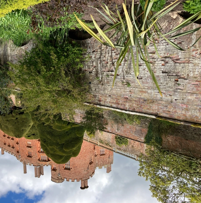 View of a castle high up on a hill from the garden pathway.