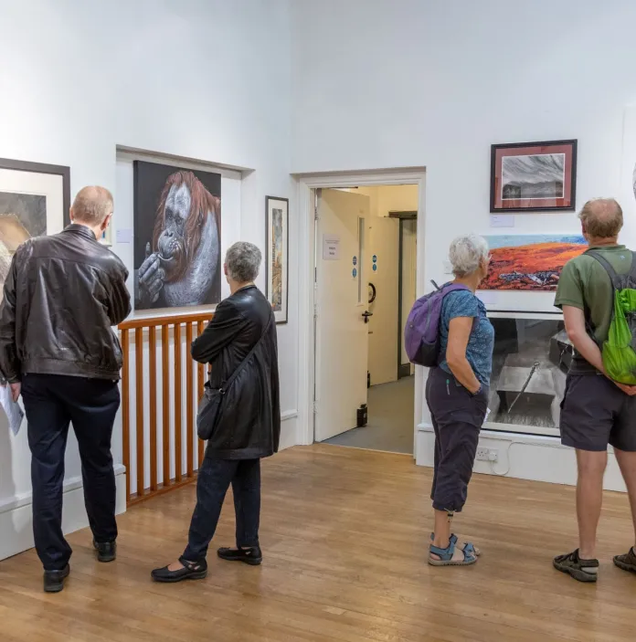 Group of people looking at artwork in a gallery.