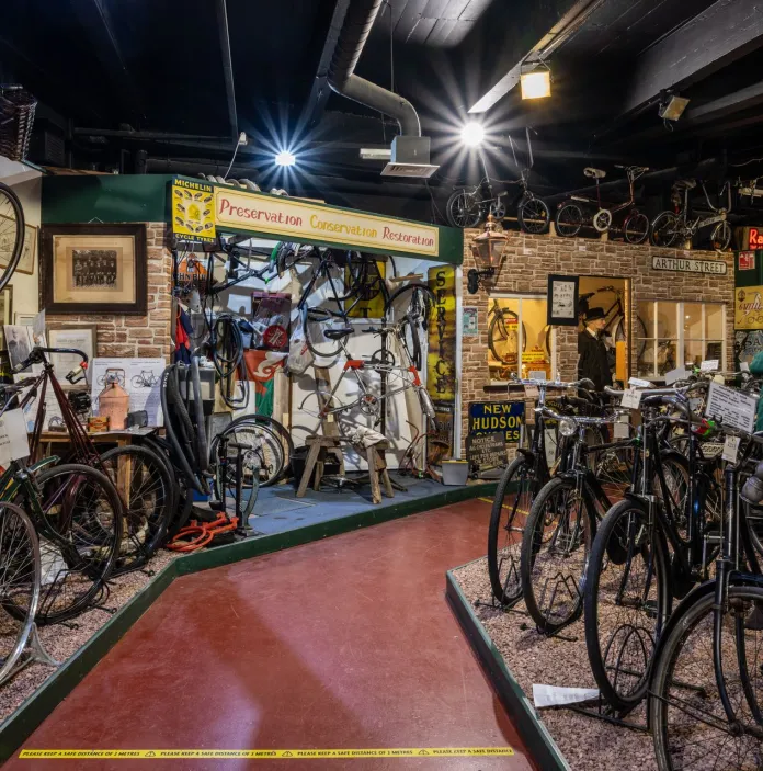 A lot of old bikes on display in a museum.