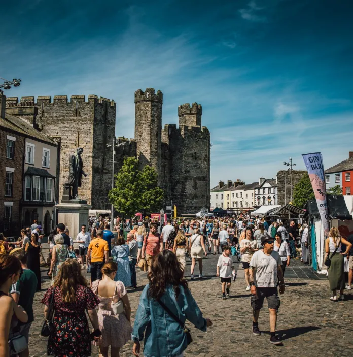 People walking around a food festival with a castle in the background.