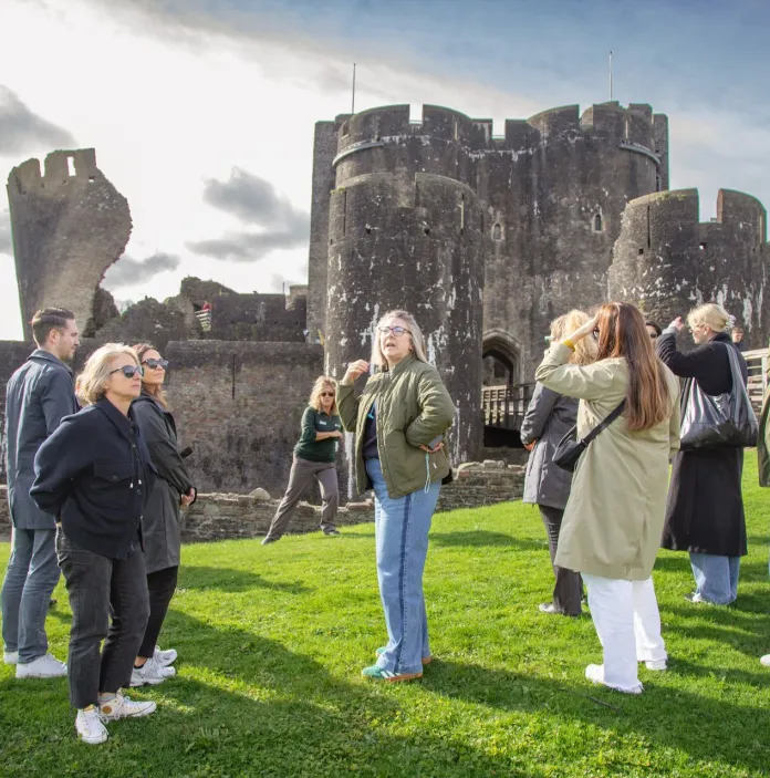 Group of people exploring a castle with a leaning tower.