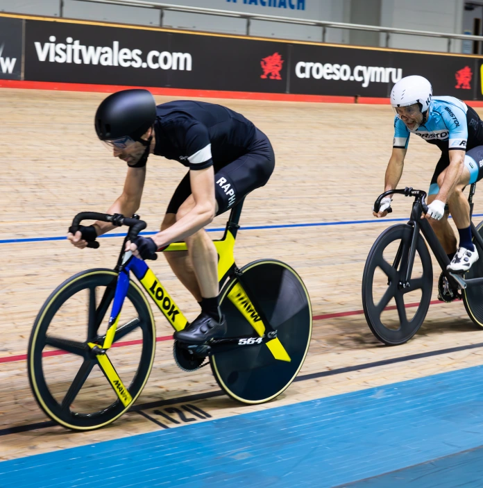 Two cyclists on a track session at a cycling velodrome.