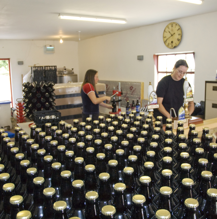 Two ladies working at Gwaun Valley Brewery with hundreds of bottles of beer in the foreground.