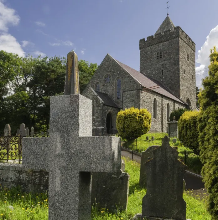St David's Church and the graveyard with a cross and gravestones in the foreground.