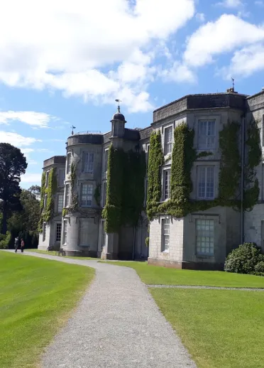 A grand house covered in Ivy with views of the river beyond.