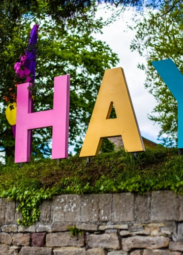 Colourful large letters on a wall spelling HAY next to colourful flags.