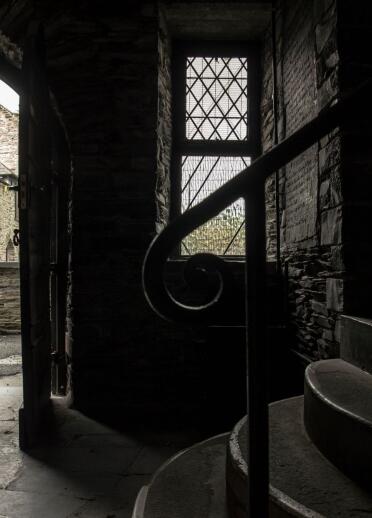 A dark atmospheric image of inside the Owain Glyndwr Centre with a view of the courtyard from the arch door.