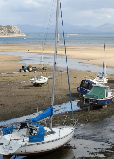 Boats and yachts moored on the beach with the tide out on Abersoch beach.