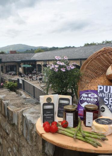 Welsh products displayed on a stone wall outside Bodnant Welsh Food Centre.