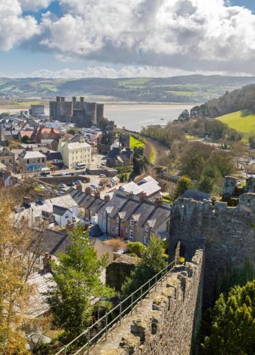 Aerial view of Conwy Town Walls with castle, sea and mountains.
