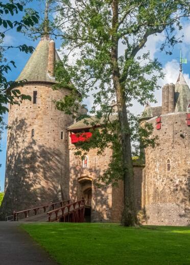The turrets and entrance to a fairytale castle surrounded by trees.