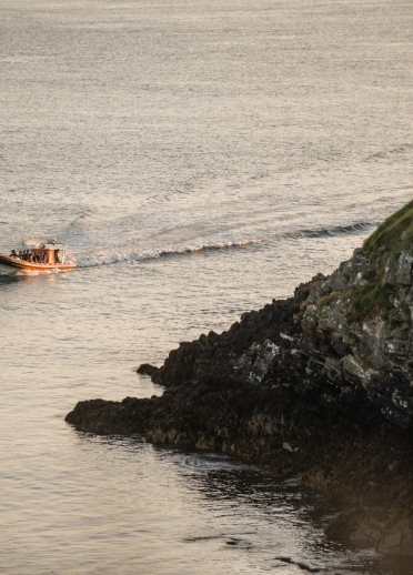 A pleasure boat filled with people sailing into the bay.