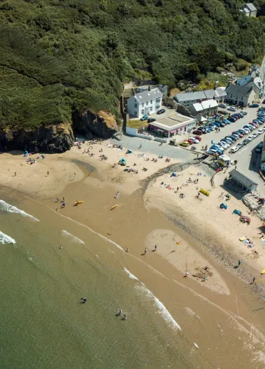 An aerial shot of Llangrannog beach, sea and surrounding buildings.