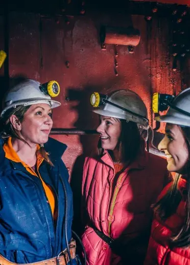 A group of people wearing mining hats and lamps with a guide.