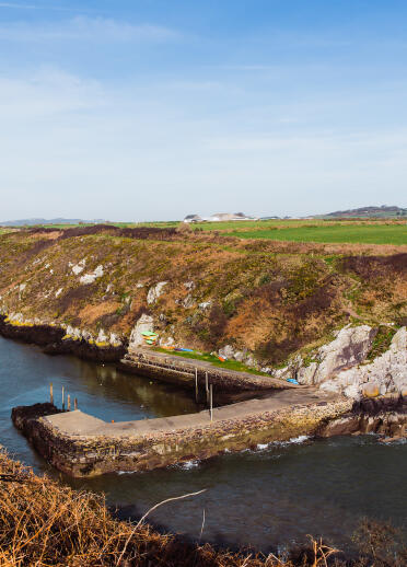A small harbour surrounded by cliffs with the tide in.