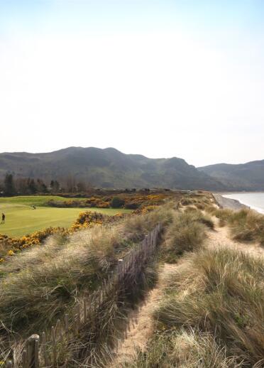 Golfers playing at Conwy golf course by the sea. 