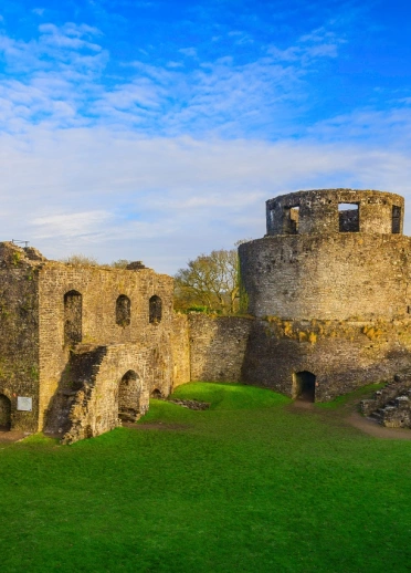 A castle on lush green lawns set against a blue sky and wispy clouds.