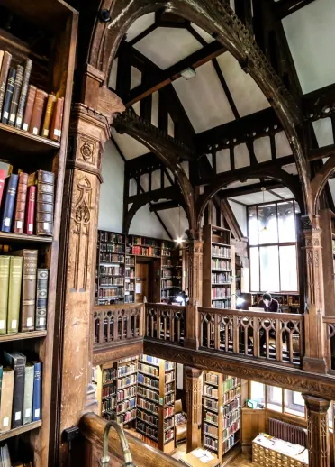 A library taken from a balcony showing shelves of books and an ornate roofspace.