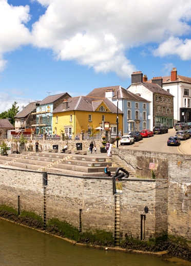 Shops and a castle on a hill leading to the quayside.