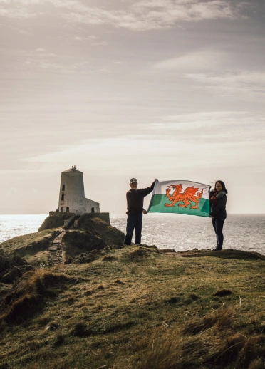 2 people holding the Welsh flag at Llanddwyn Island
