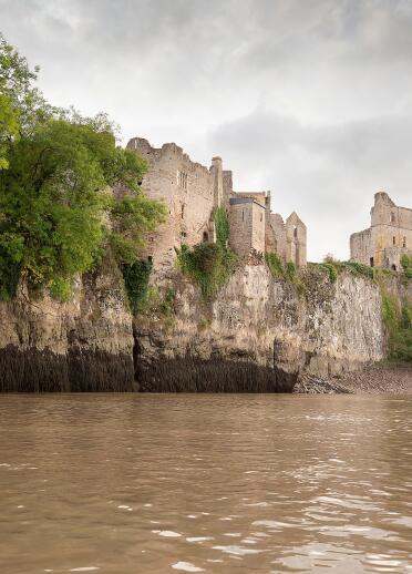 A castle perched high above the cliff against a river.
