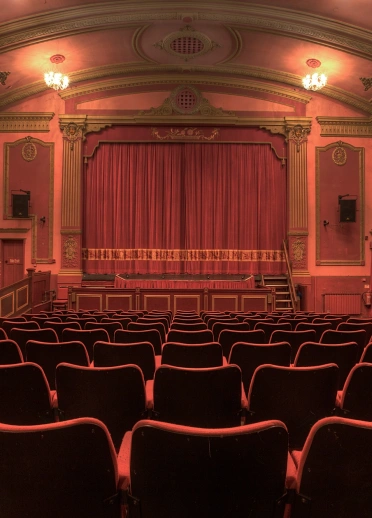 View of the curtained stage from a theatre seat.