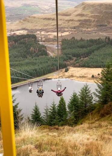 People on zip wires zipping across a mountainous landscape.
