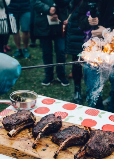 A chef cooking meat at an outdoor food festival.