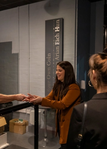 A lady being presented with a coin straight off the press in presentation pack.