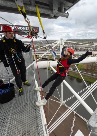 A women preparing to abseil down a sports stadium.