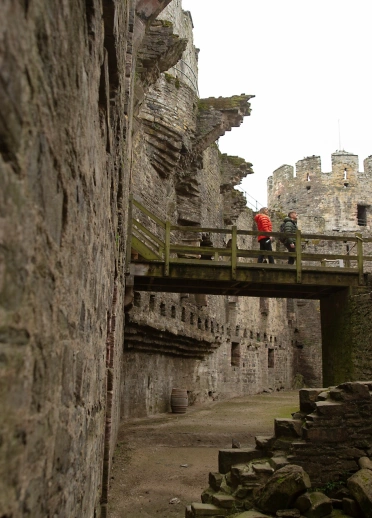 Couple on a wooden bridge crossing between two castle walls.