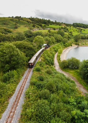 A train in the countryside passing a reservoir.