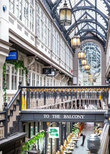 Ornate features and a glass room on the balcony of a Victorian shopping arcade.