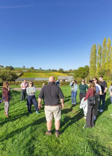 Group of people in a field on a tour of a vineyard.