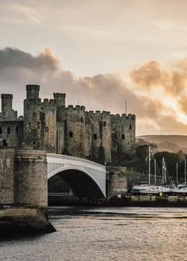 A bridge over the water leading to a castle and harbour.