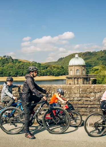 Family of cyclists passing a lake.