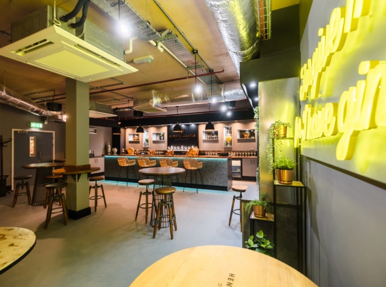 A bar in a distillery with a neon lit sign on the wall.